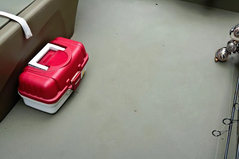 Slide: The Image of A red tackle box sits on the floor of a boat next to fishing rods. - 23