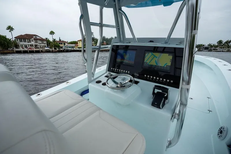 Slide: The Image of 2019 Conch 33 boat interior with dual navigation screens, steering wheel, and waterfront view. - 28