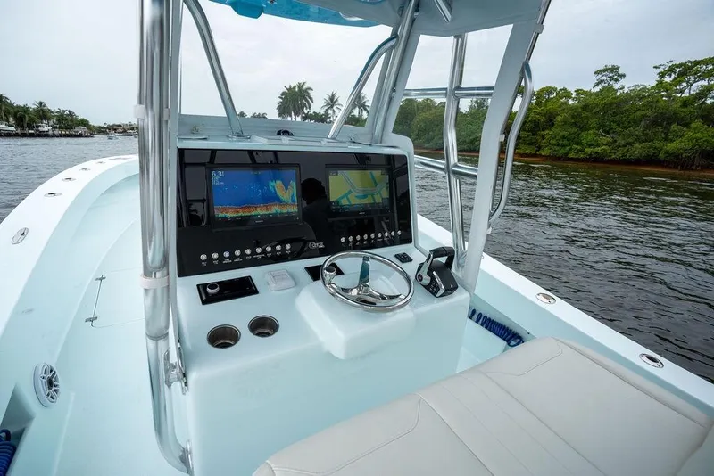 Slide: The Image of 2019 Conch 33 boat dashboard with navigation screens and steering wheel on a calm waterway. - 23