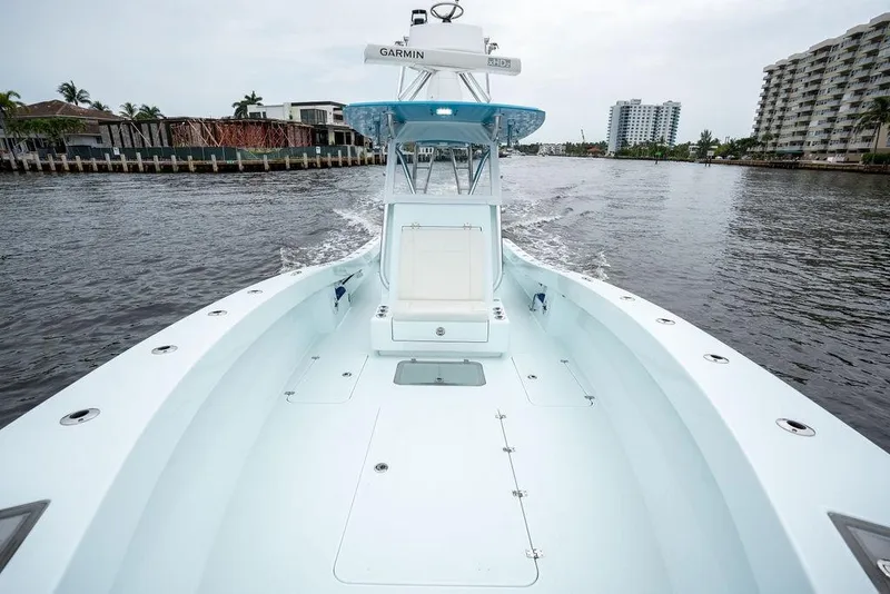 Slide: The Image of 2019 Conch 33 boat cruising on a calm waterway, surrounded by waterfront buildings. - 19