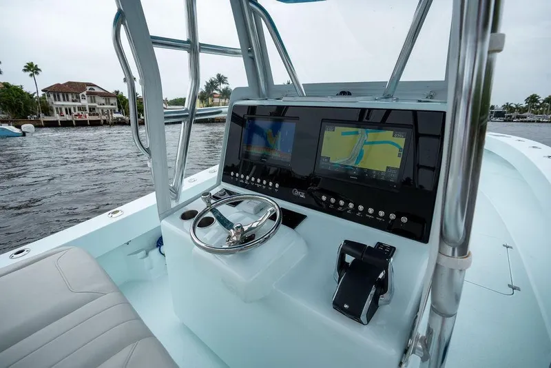 Slide: The Image of 2019 Conch 33 boat dashboard with dual navigation screens on a calm waterway. - 26