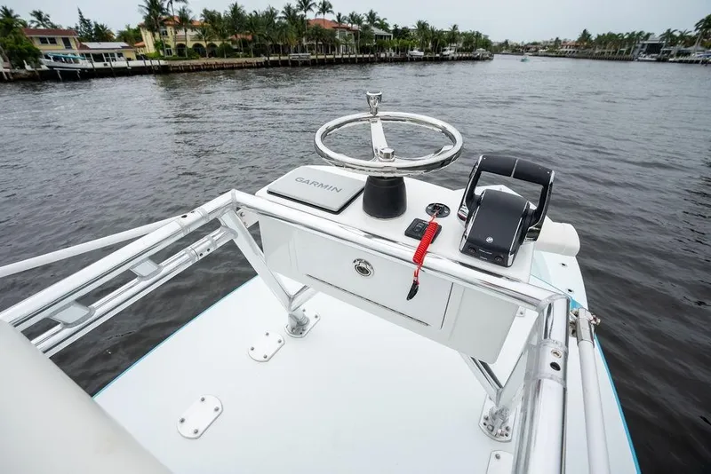 Slide: The Image of 2019 Conch 33 boat helm with Garmin navigation, steering wheel, and throttle controls on a calm waterway. - 32