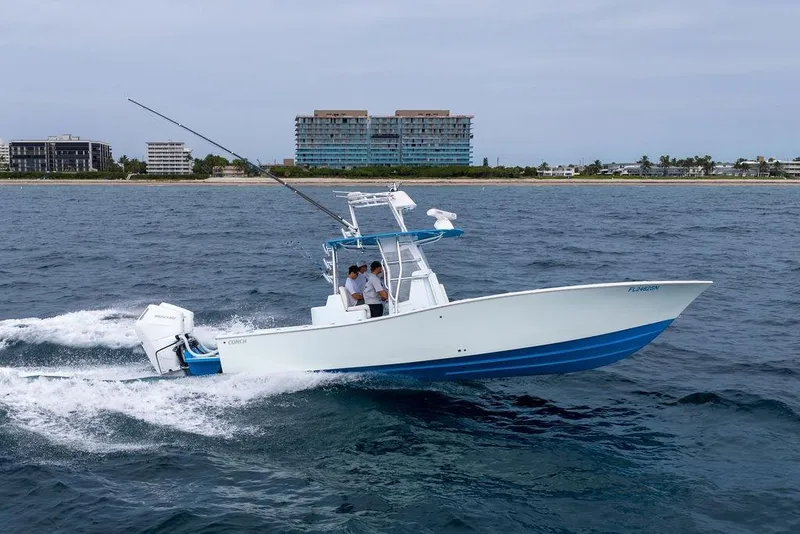 Slide: The Image of 2019 Conch 33 boat cruising on the ocean near a coastal cityscape. - 4