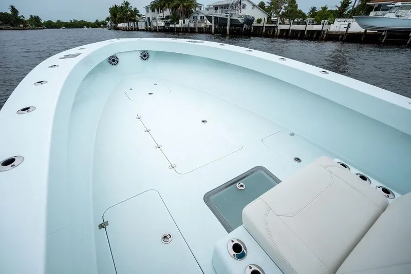 Slide: The Image of 2019 Conch 33 boat interior with spacious deck and seating, docked by waterfront homes. - 14