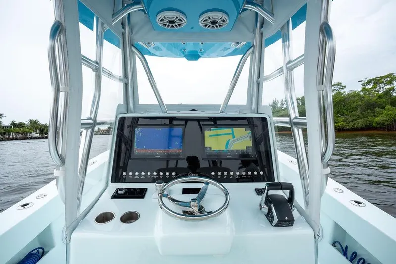 Slide: The Image of 2019 Conch 33 boat dashboard with navigation screens and steering wheel on a calm waterway. - 25