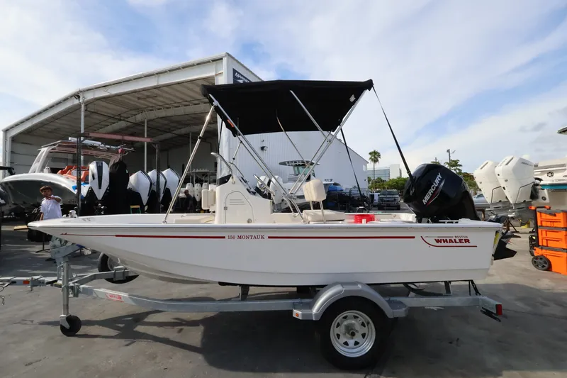 Slide: The Image of A 2027 Boston Whaler 150 Montauk on a trailer in a boat storage area. - 1