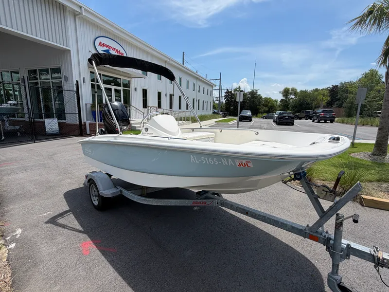 Slide: The Image of A white 2018 Boston Whaler 130 Super Sport boat on a trailer in front of a building. - 2