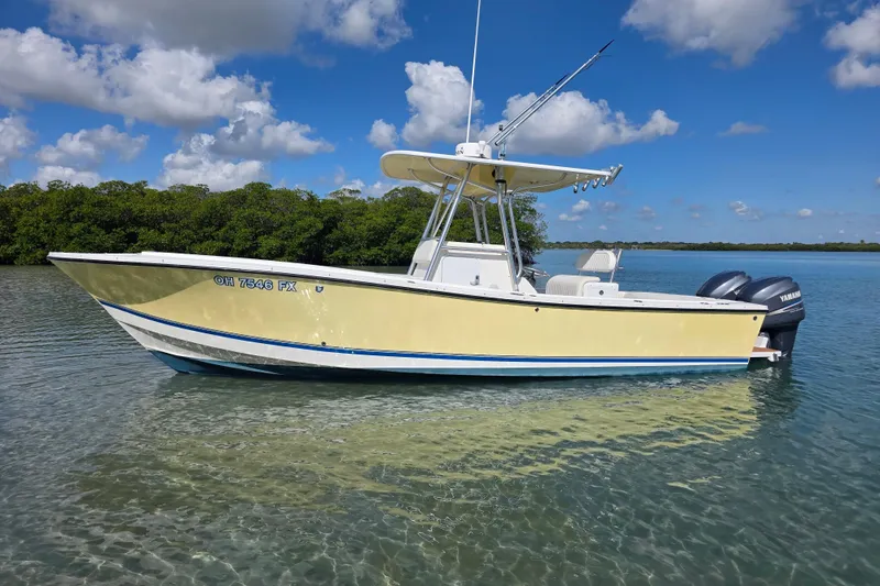 The Image of 2002 Regulator 26 Center Console boat on calm water under a clear blue sky. - 1
