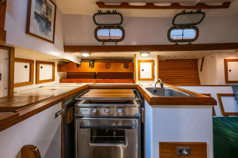 Slide: The Image of Interior of 1981 Morris Yachts Leigh 30, featuring a compact kitchen with stove and sink. - 15