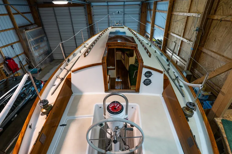 Slide: The Image of 1981 Morris Yachts Leigh 30 sailboat interior, showcasing cockpit and cabin entrance in a wooden boathouse. - 10