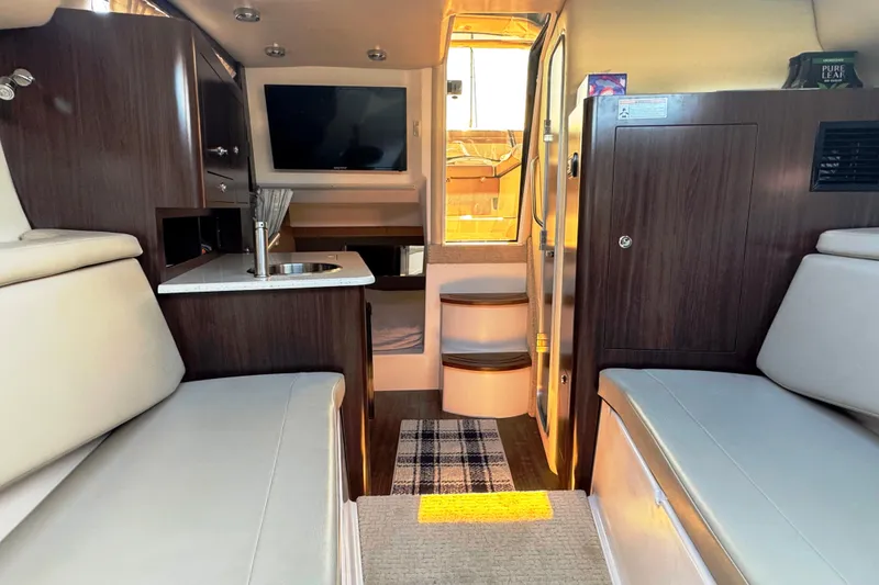 Slide: The Image of Interior of 2017 Regal 30 Express boat with seating, kitchenette, and TV. - 19