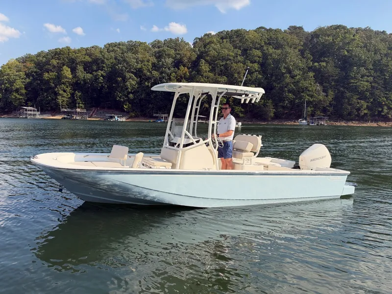 Slide: The Image of A 2027 Boston Whaler 210 Montauk on a calm lake with a wooded shoreline in the background. - 42