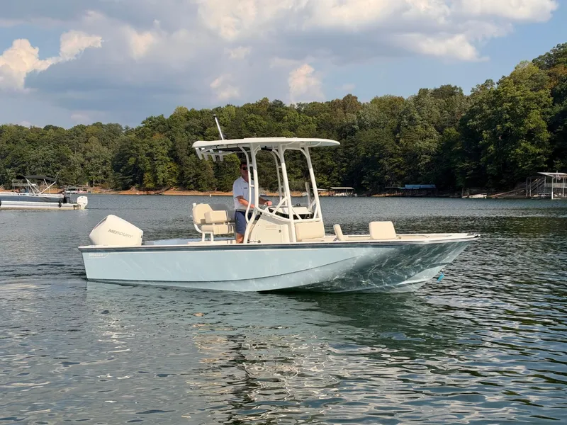 Slide: The Image of A 2027 Boston Whaler 210 Montauk on a calm lake with a wooded shoreline. - 36