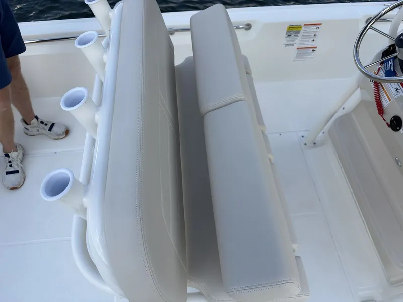 Slide: The Image of The 2027 Boston Whaler 210 Montauk features a white cushioned bench with integrated rod holders. - 14