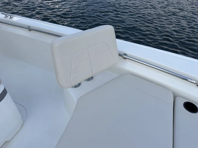 Slide: The Image of The 2027 Boston Whaler 210 Montauk features a sleek, white bench seat by the water. - 23
