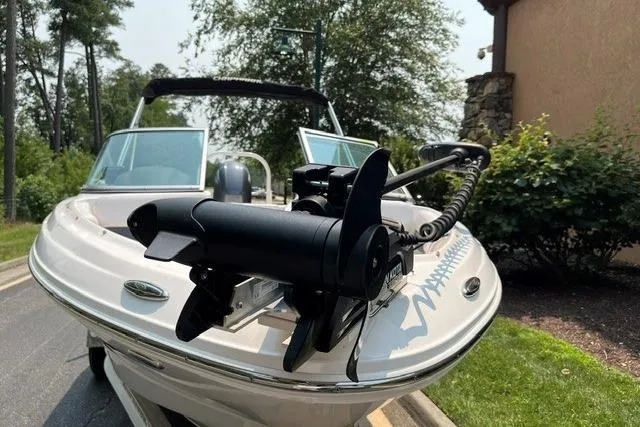 Slide: The Image of 2021 Chaparral 19 SSi OB boat with trolling motor, parked on a driveway. - 2
