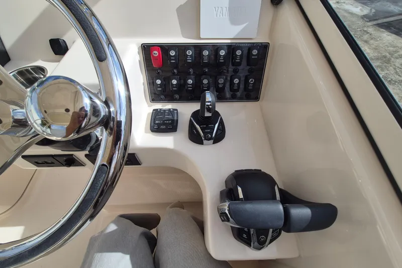 Slide: The Image of Helm of 2026 Grady-White Freedom 275 boat with steering wheel and control panel. - 10