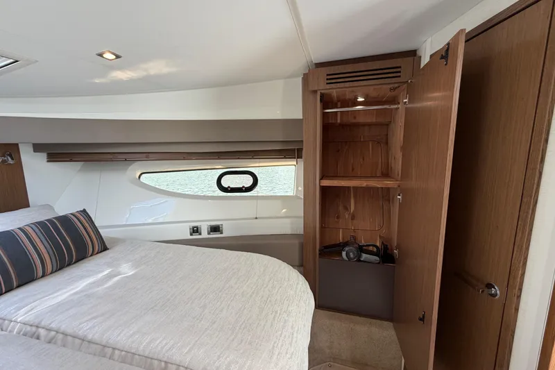 Slide: The Image of Interior of 2017 Sea Ray Sundancer 460 yacht with open wooden cabinet and bed. - 36