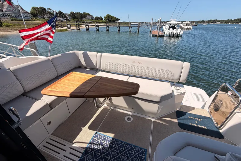 Slide: The Image of 2017 Sea Ray Sundancer 460 yacht deck with seating, table, and American flag by the water. - 13