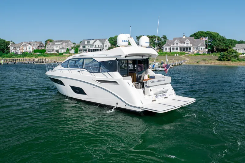 Slide: The Image of 2017 Sea Ray Sundancer 460 yacht cruising near waterfront homes on a sunny day. - 2
