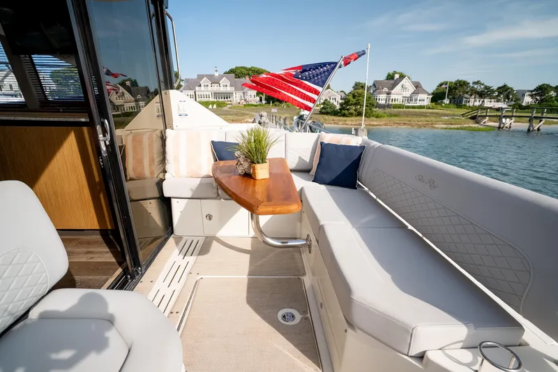 Slide: The Image of Luxurious 2017 Sea Ray Sundancer 460 yacht with elegant seating and American flag, docked by waterfront homes. - 26