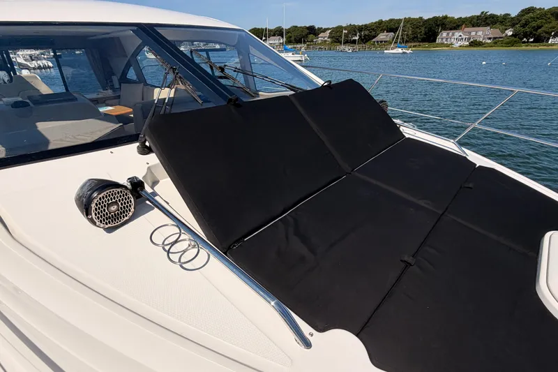 Slide: The Image of 2017 Sea Ray Sundancer 460 yacht with sunbathing deck, docked near a scenic shoreline. - 7