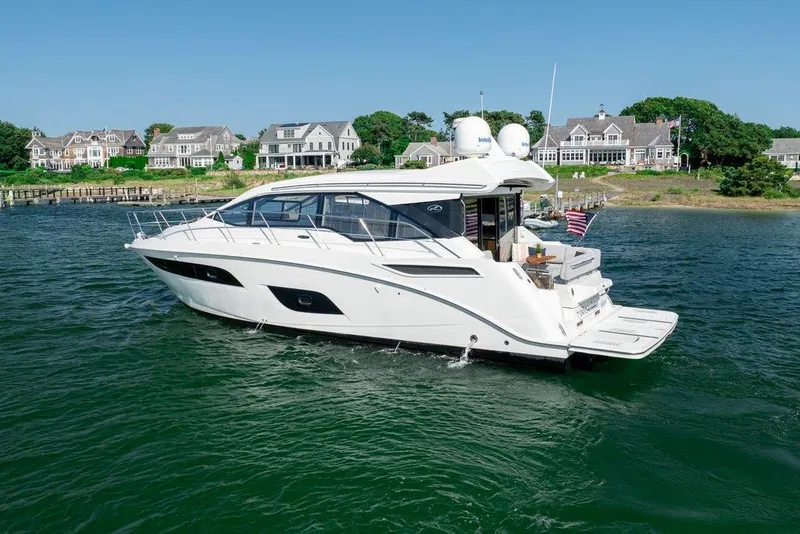 The Image of 2017 Sea Ray Sundancer 460 yacht cruising near coastal homes. - 1