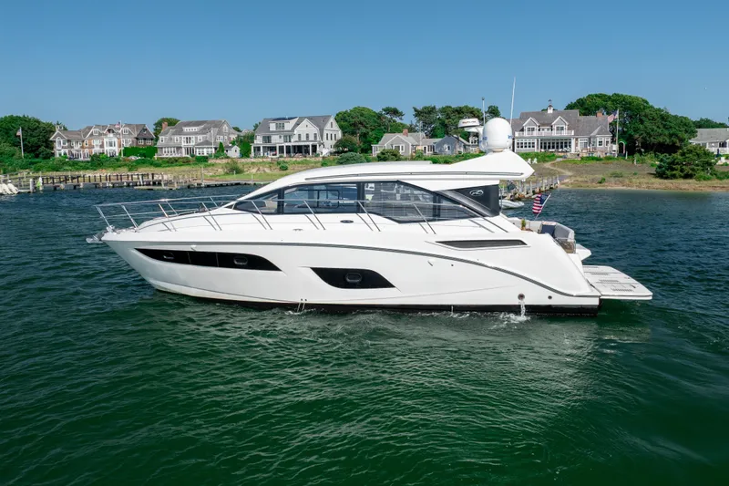 Slide: The Image of 2017 Sea Ray Sundancer 460 yacht cruising near coastal homes on a sunny day. - 0