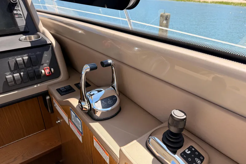 Slide: The Image of 2017 Sea Ray Sundancer 460 helm controls with throttle and joystick, dockside view. - 26