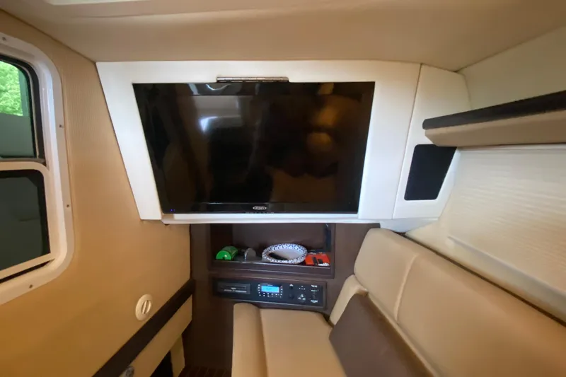 Slide: The Image of Interior of a 2015 Cobalt 336 boat featuring a mounted TV and cozy seating area. - 44
