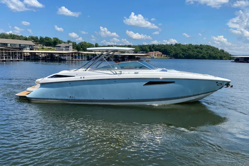 Slide: The Image of 2015 Cobalt 336 boat on a lake, clear sky, surrounded by docks and trees. - 5