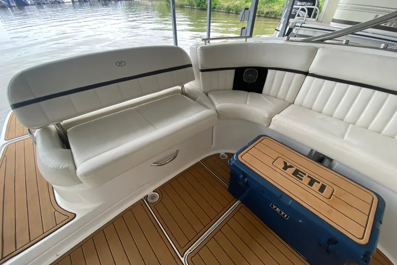 Slide: The Image of 2015 Cobalt 336 boat interior with white seating and Yeti cooler on teak flooring. - 20