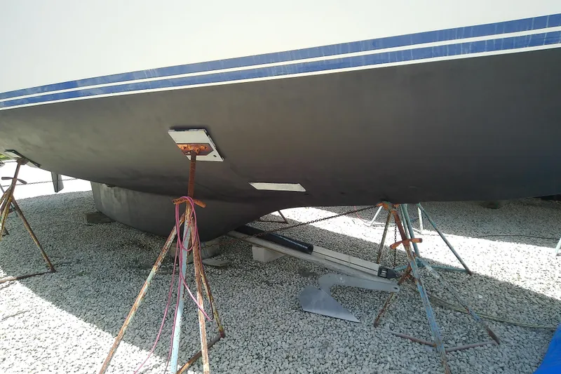 Slide: The Image of 1988 Brewer 44 sailboat hull on stands, displayed on gravel surface. - 15