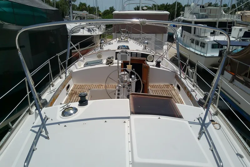 Slide: The Image of 1988 Brewer 44 sailboat deck view, showcasing helm and seating area in marina. - 25