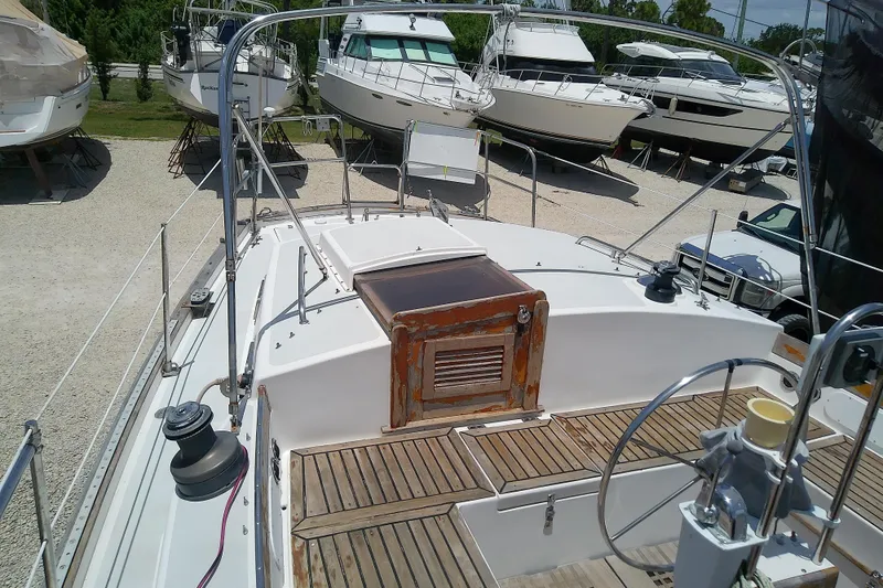 Slide: The Image of 1988 Brewer 44 sailboat deck with wooden accents, surrounded by other boats on land. - 22