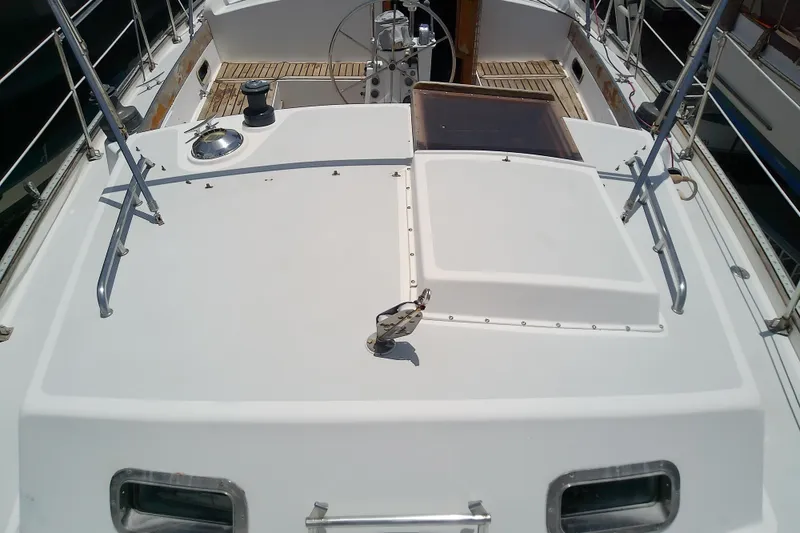 Slide: The Image of Deck view of a 1988 Brewer 44 sailboat, featuring a clean, white surface and metal railings. - 24
