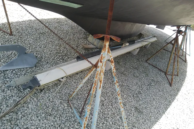 Slide: The Image of Rusty boat stands supporting a 1988 Brewer 44 hull on gravel. - 4