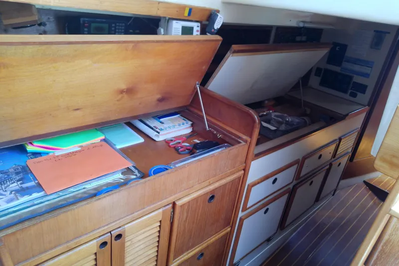Slide: The Image of Interior of a 1988 Brewer 44 sailboat with open wooden cabinets and navigation equipment. - 60