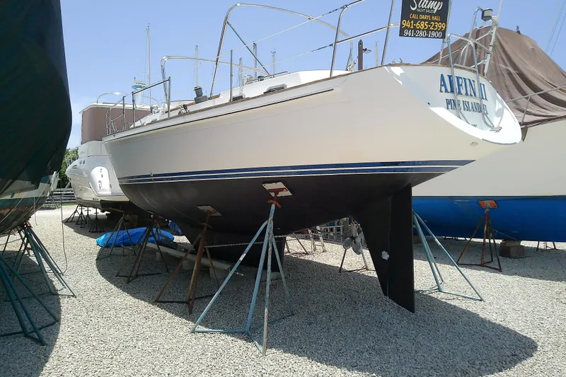 Slide: The Image of 1988 Brewer 44 sailboat on stands, displayed outdoors on gravel. - 6