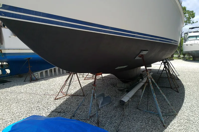 Slide: The Image of 1988 Brewer 44 sailboat on stands, hull painted black, in a gravel boatyard. - 5