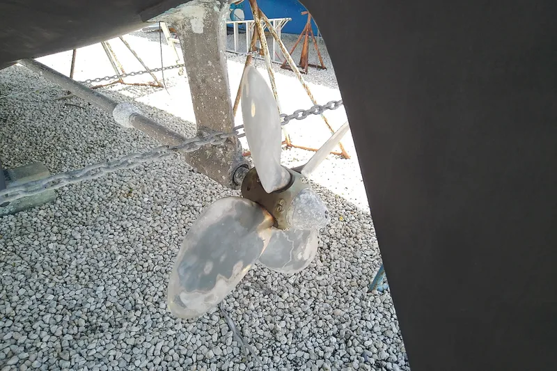 Slide: The Image of Propeller of a 1988 Brewer 44 sailboat on gravel, with visible chains and supports. - 12