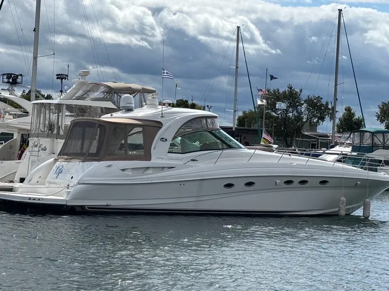 The Image of A 2003 Sea Ray 500 Sundancer is docked in the water, surrounded by other boats in the marina. - 0