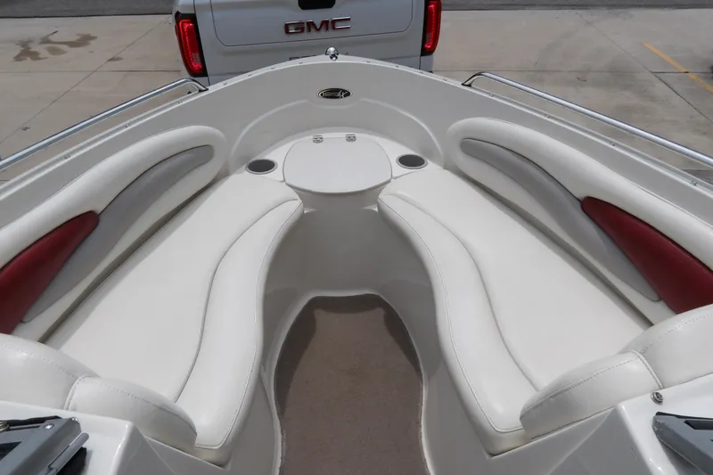 Slide: The Image of 2012 Stingray 195 LS/LX boat interior with white and red seating, parked near a GMC vehicle. - 18