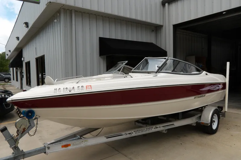 Slide: The Image of 2012 Stingray 195 LS/LX boat on trailer outside a metal building. - 2