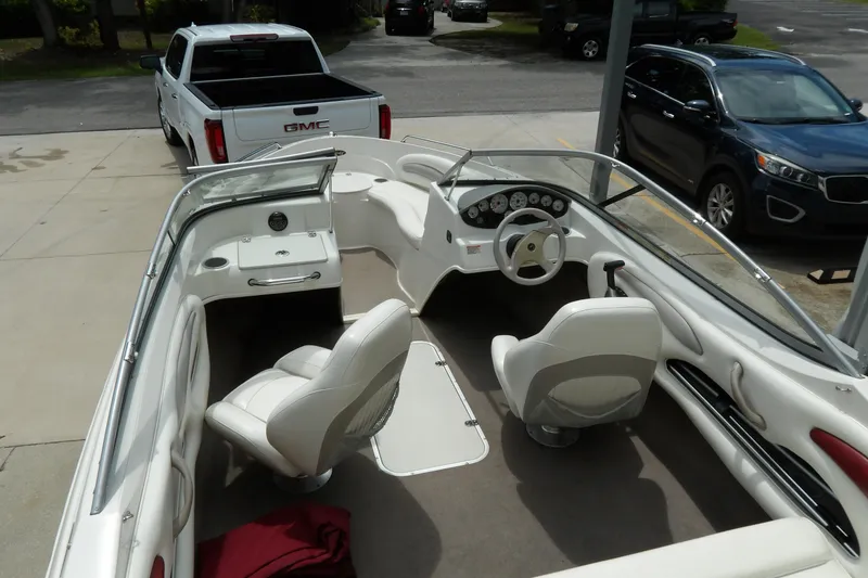 Slide: The Image of 2012 Stingray 195 LS/LX boat interior with white seating, parked near a GMC truck. - 13