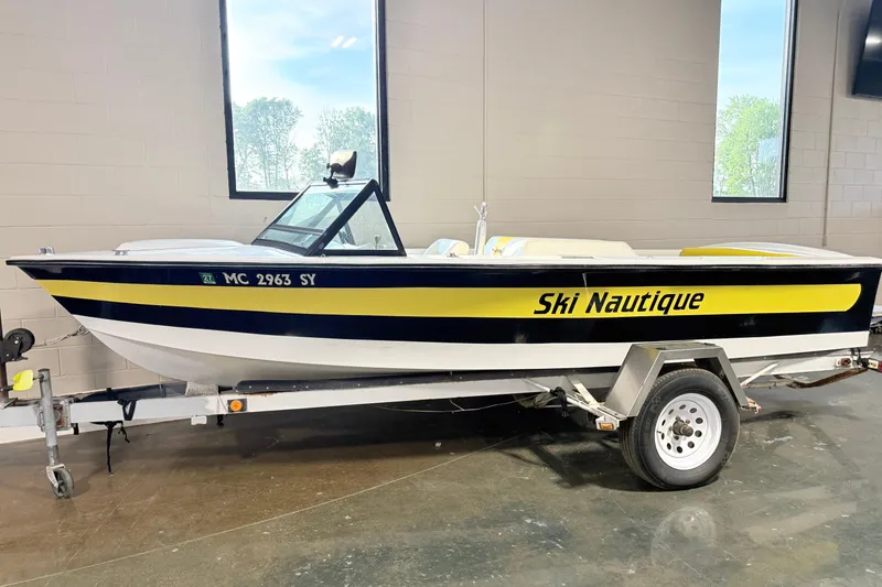 The Image of 1978 Correct Craft Ski Nautique boat on trailer, indoors, with yellow and black detailing. - 0