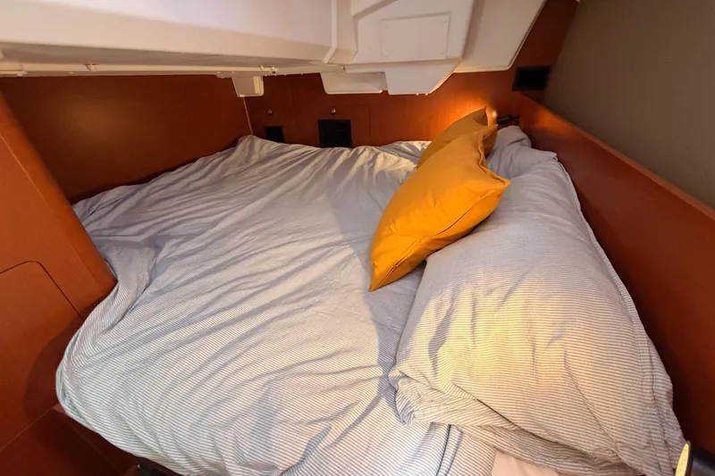 Slide: The Image of Cozy cabin bed in 2018 Beneteau Oceanis 35.1 yacht with striped bedding and orange pillow. - 46