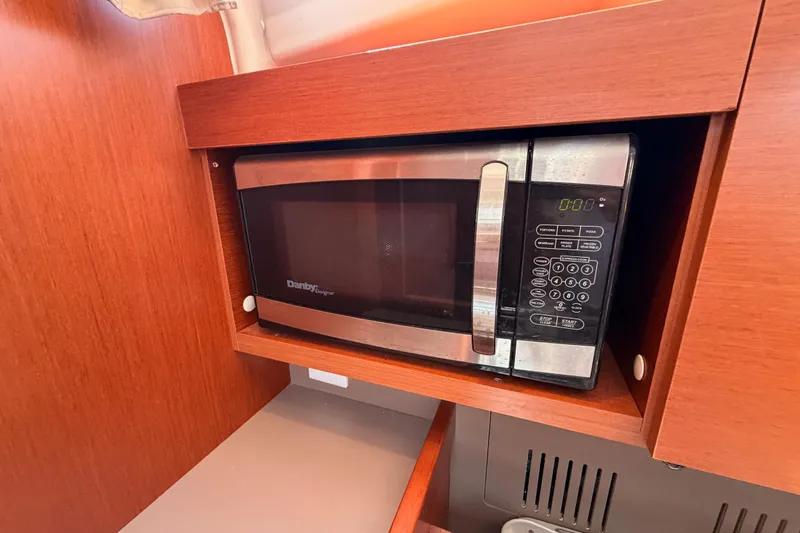 Slide: The Image of Microwave in 2018 Beneteau Oceanis 35.1 yacht kitchen, featuring wood cabinetry. - 43