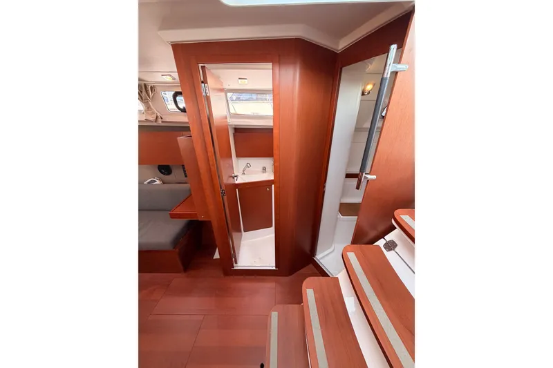 Slide: The Image of Interior of 2018 Beneteau Oceanis 35.1 yacht, featuring wooden cabinetry and compact bathroom. - 50