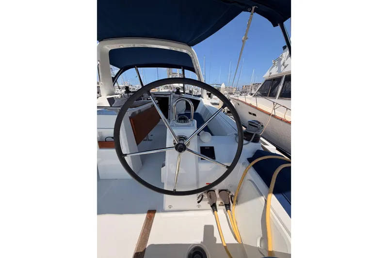 Slide: The Image of Cockpit view of 2018 Beneteau Oceanis 35.1 sailboat with steering wheel and marina backdrop. - 24